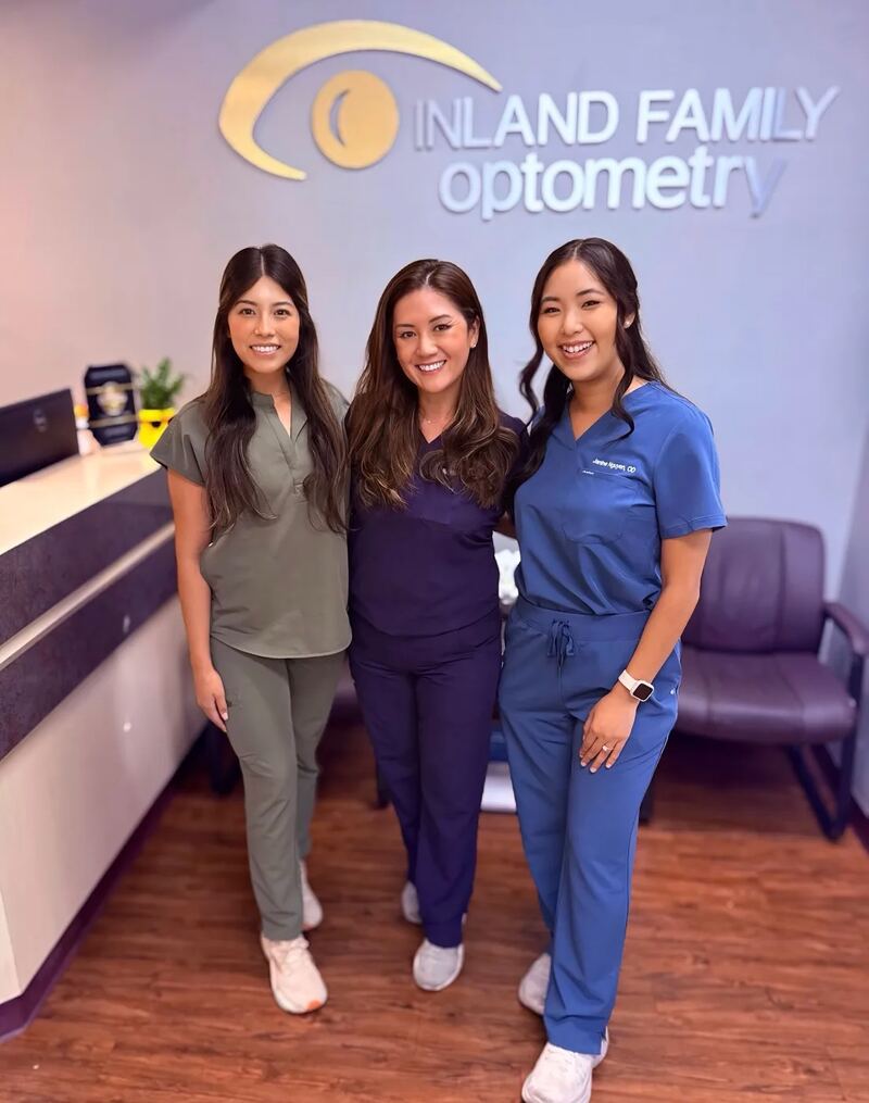 Three Inland Family Optometry team members smiling together in the reception area